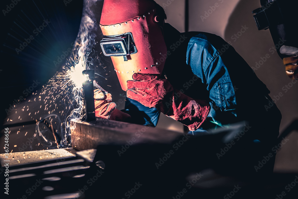 Metal welding steel works using electric arc welding machine to weld steel at factory. Metalwork man