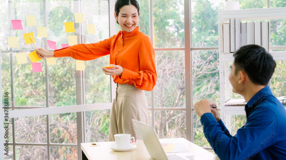 Business people work on project planning board in office and having conversation with coworker frien