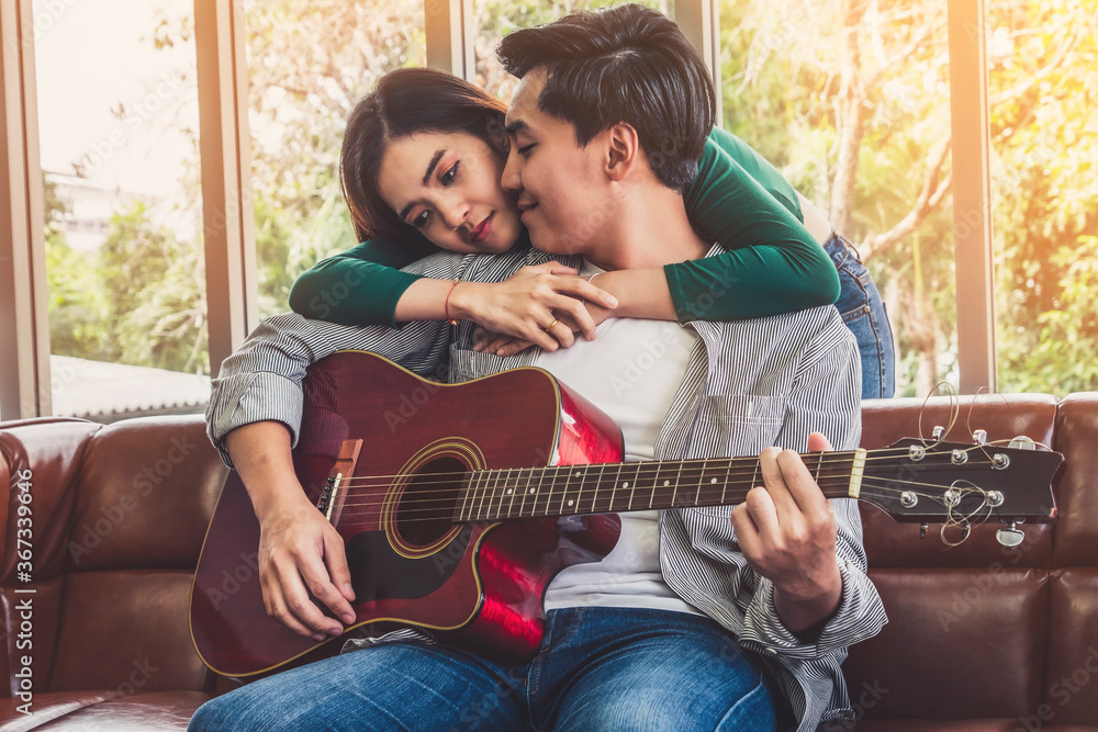 Young Asian Couple Plays Guitar and Sing Song in Living Room at Home Together. Music and Lifestyle c