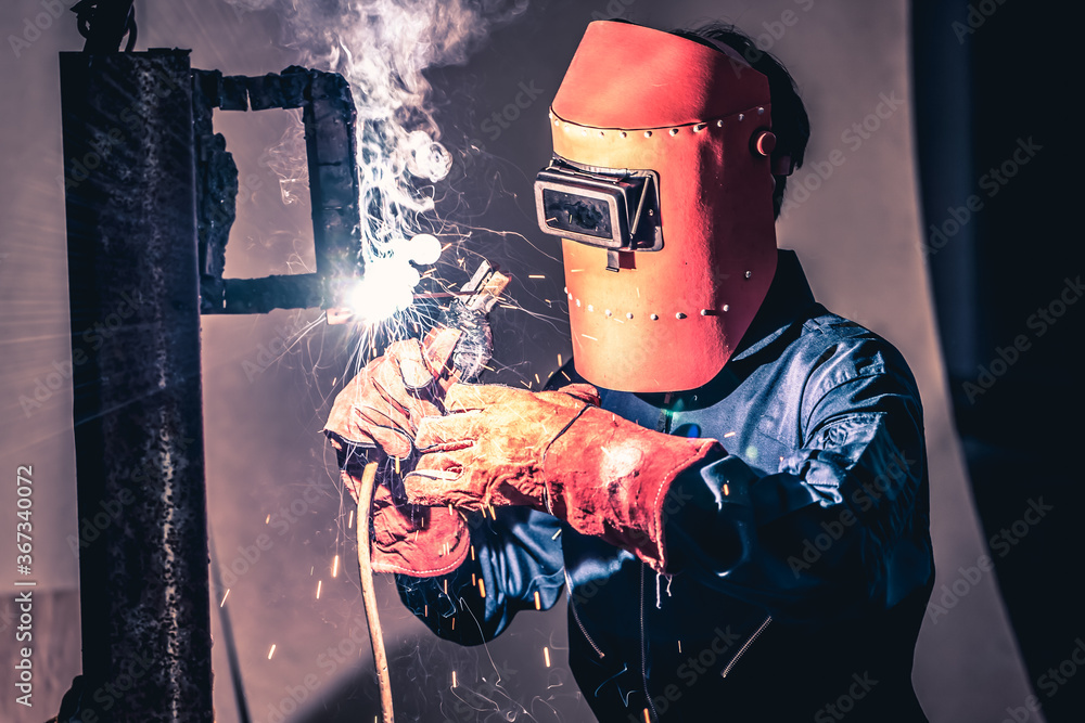 Metal welding steel works using electric arc welding machine to weld steel at factory. Metalwork man