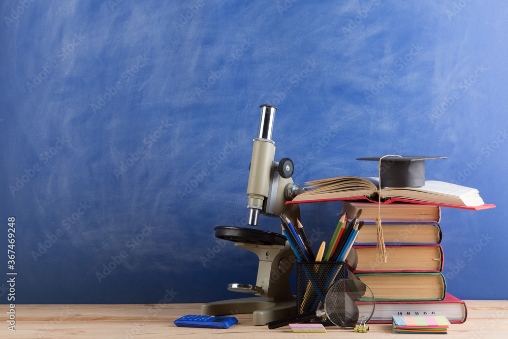 Education and sciences concept - books on the teacher desk in the auditorium, chalkboard on the back