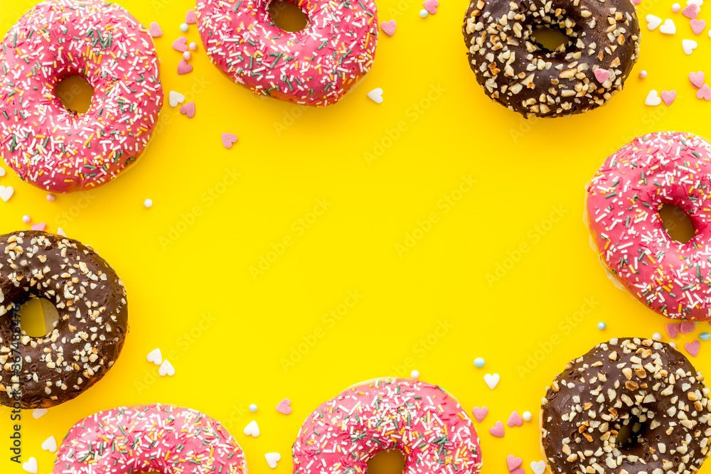 Frame of donuts with icing and sprinkles, overhead view. Colorful bakery