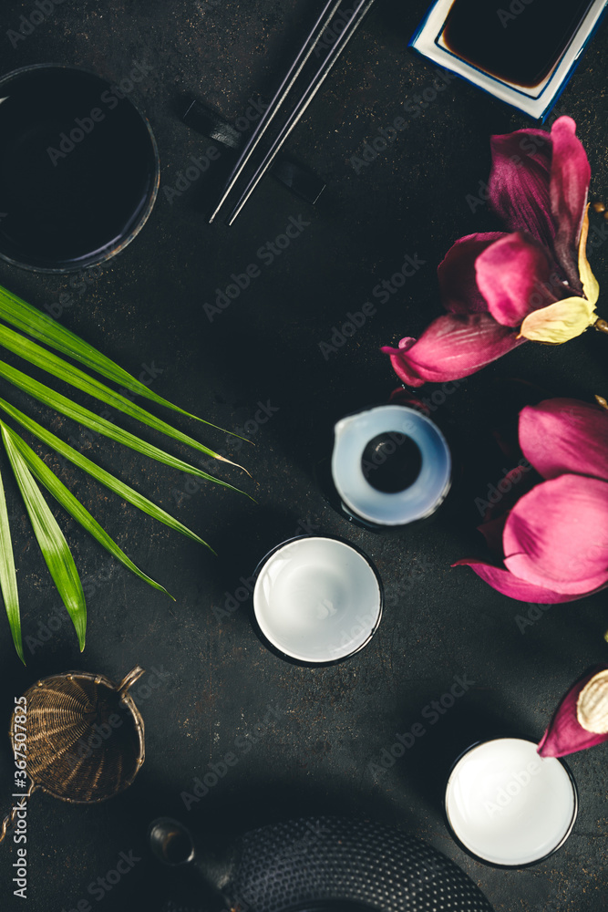 Asian food background - sake, green tea and chopsticks on dark rustic background