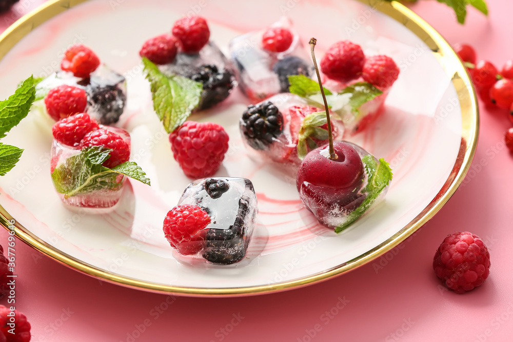 Plate with ice and frozen berries on color background