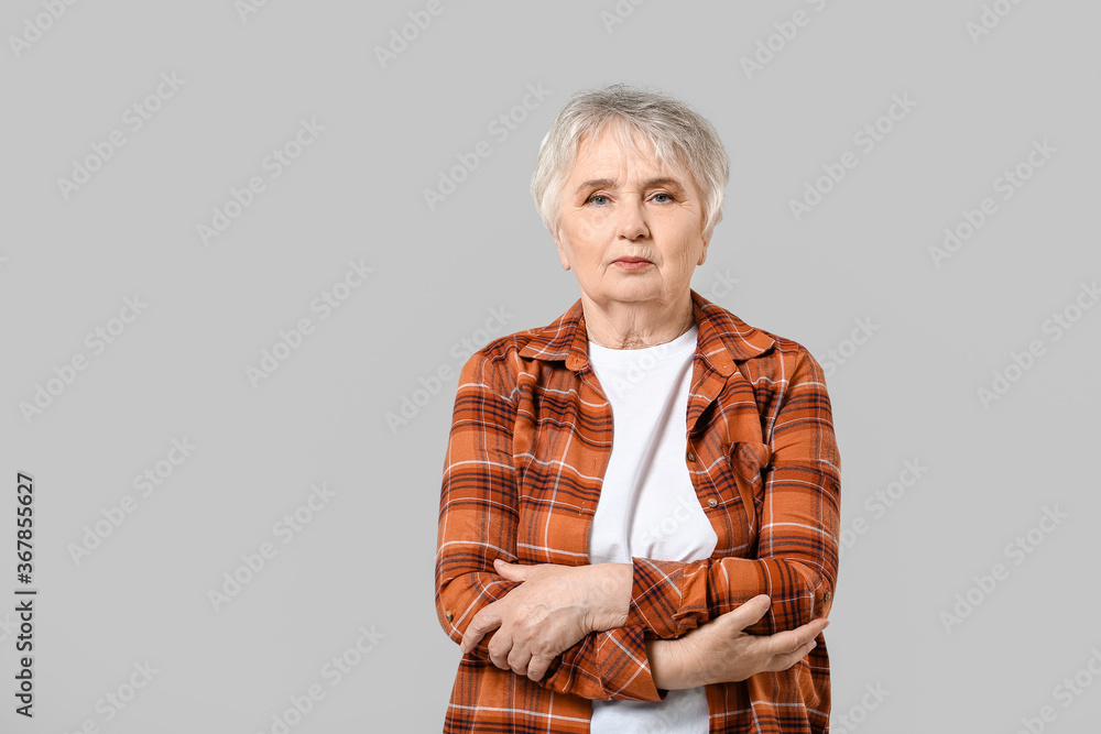 Stylish senior woman on grey background