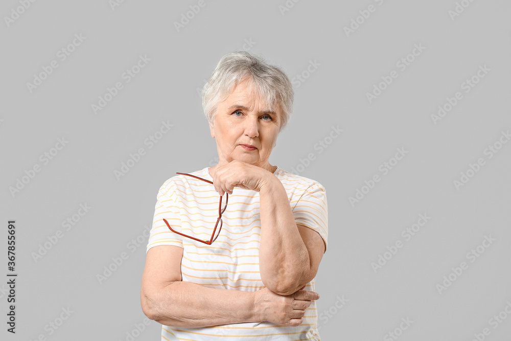 Stylish senior woman on grey background