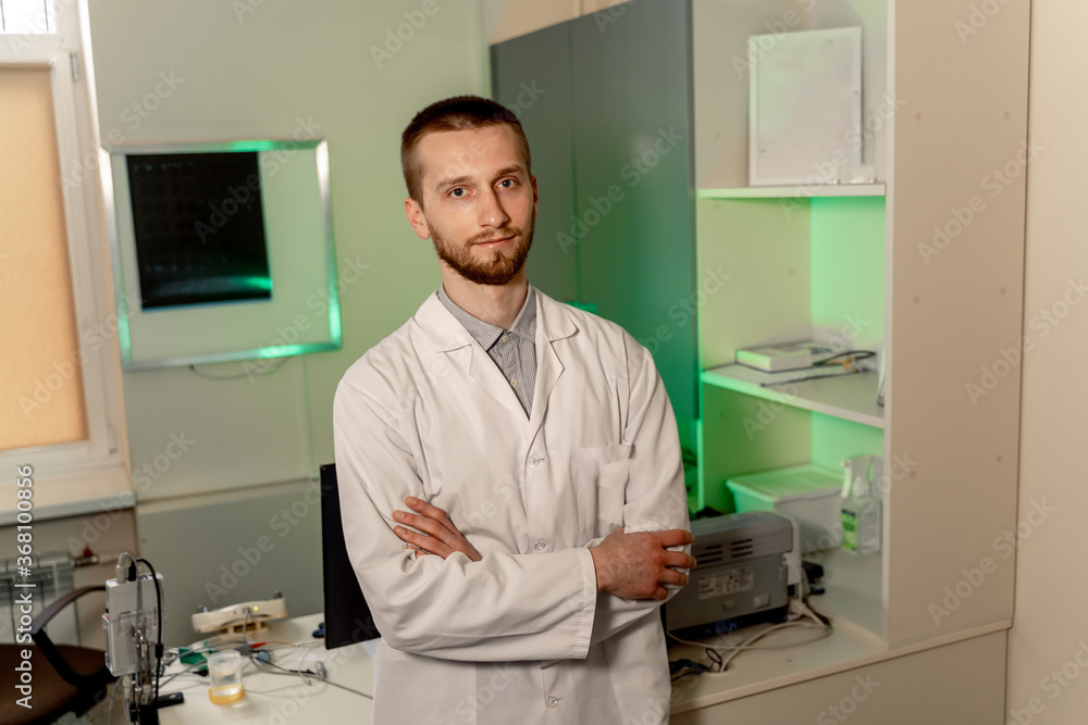 Doctor stands cross hands in office. Doctor`s working place. Office background. Modern hospital inte