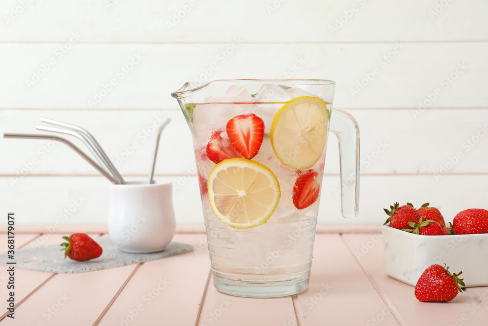 Jug of fresh strawberry lemonade on table