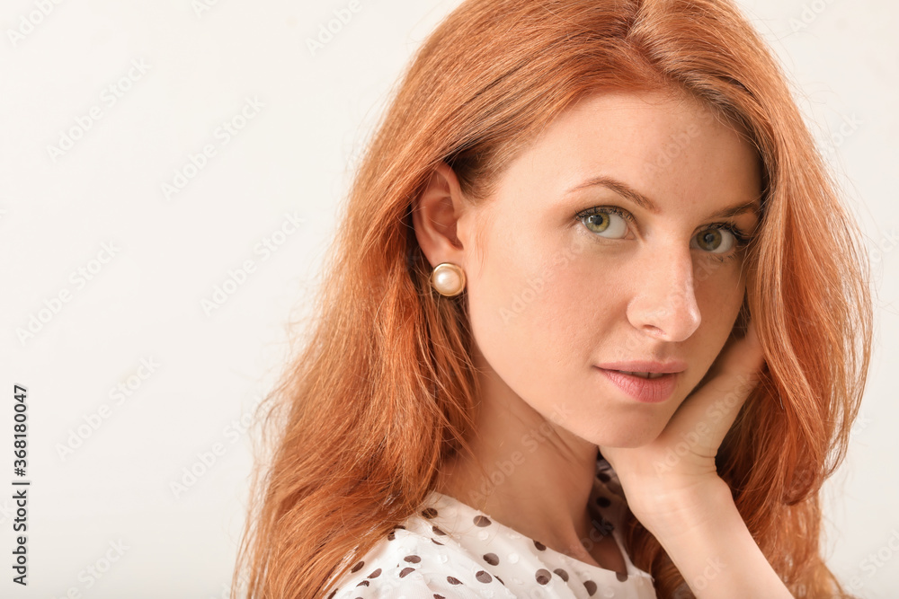 Beautiful young redhead woman on light background