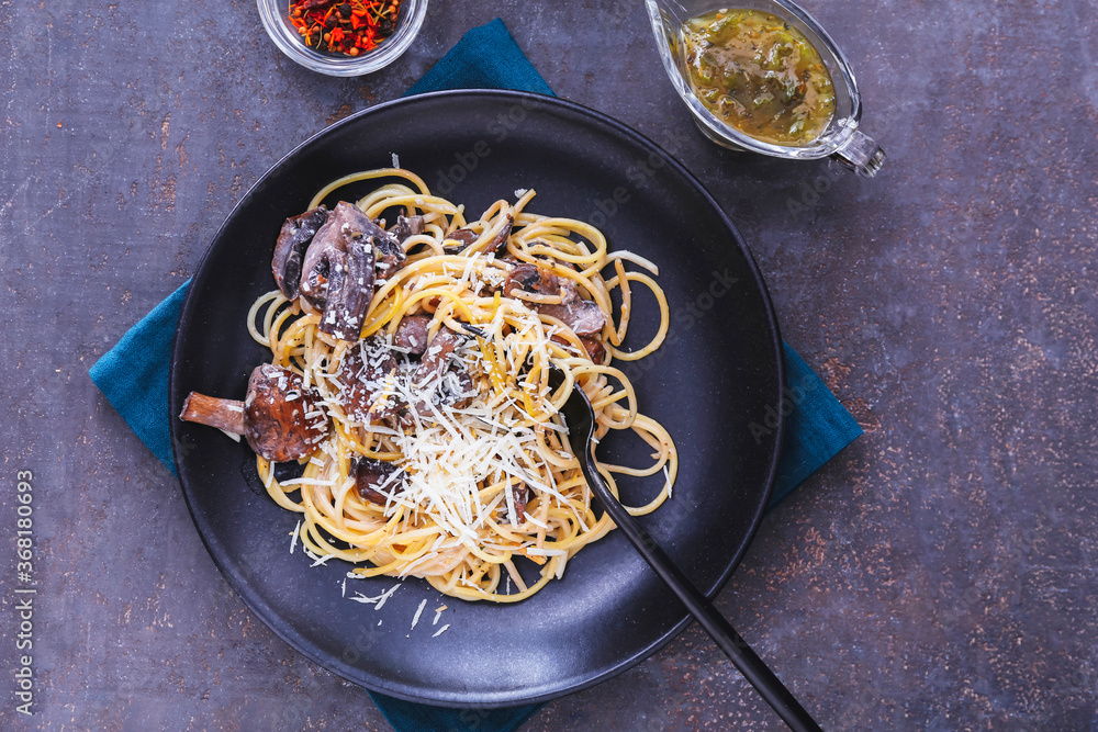 Plate with tasty pasta and mushrooms on dark background