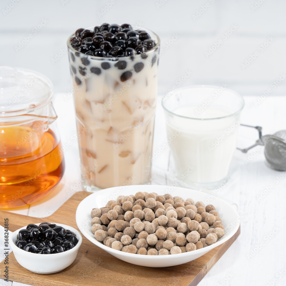 Bubble milk tea with tapioca pearl topping ingredient, famous Taiwanese drink on white wooden table 