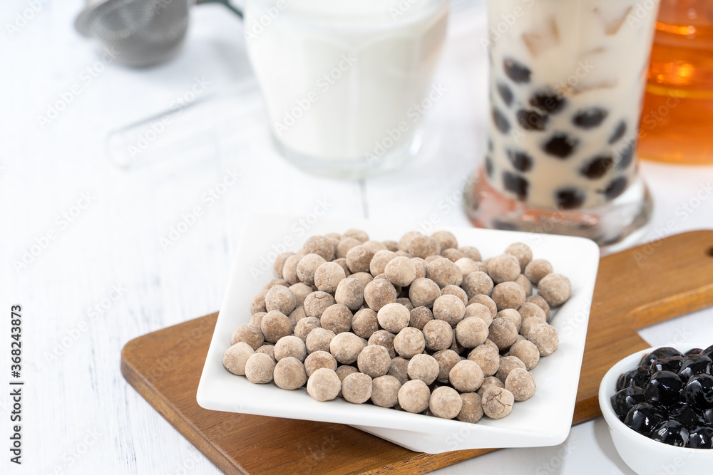 Bubble milk tea with tapioca pearl topping ingredient, famous Taiwanese drink on white wooden table 