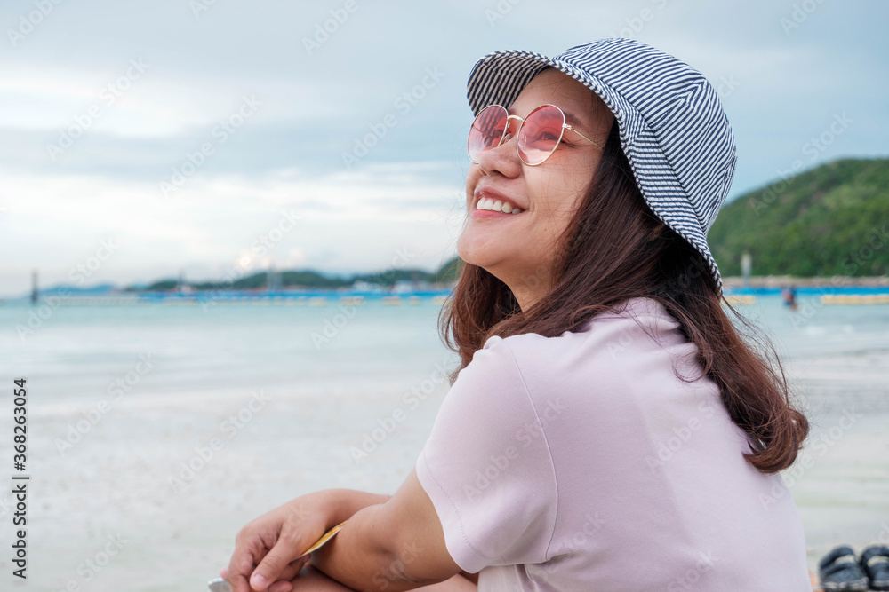 一位亚洲女游客度假时在海滩上开心地笑着。