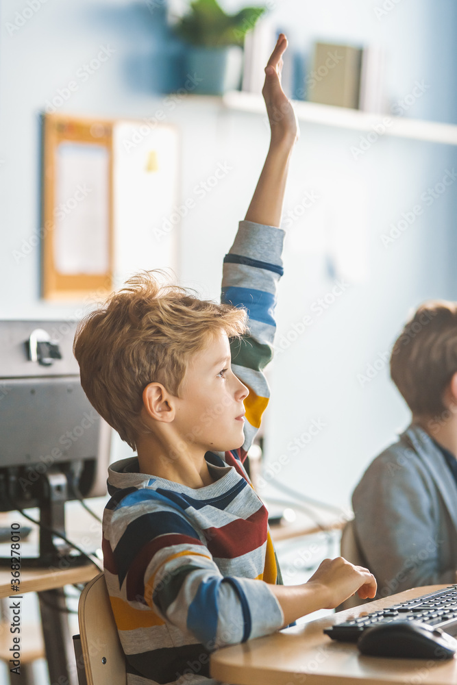 学校科学课堂：男孩举手提问。老师教育聪明的小学生