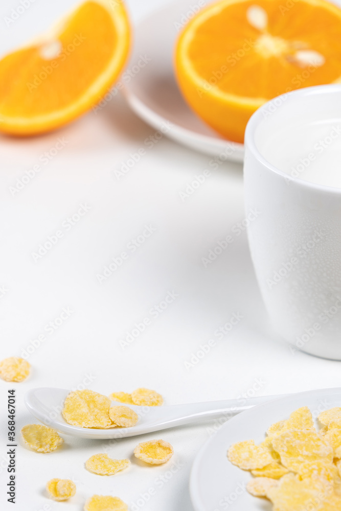 Corn flakes bowl sweeties with milk and orange on white background, close up, fresh and healthy brea