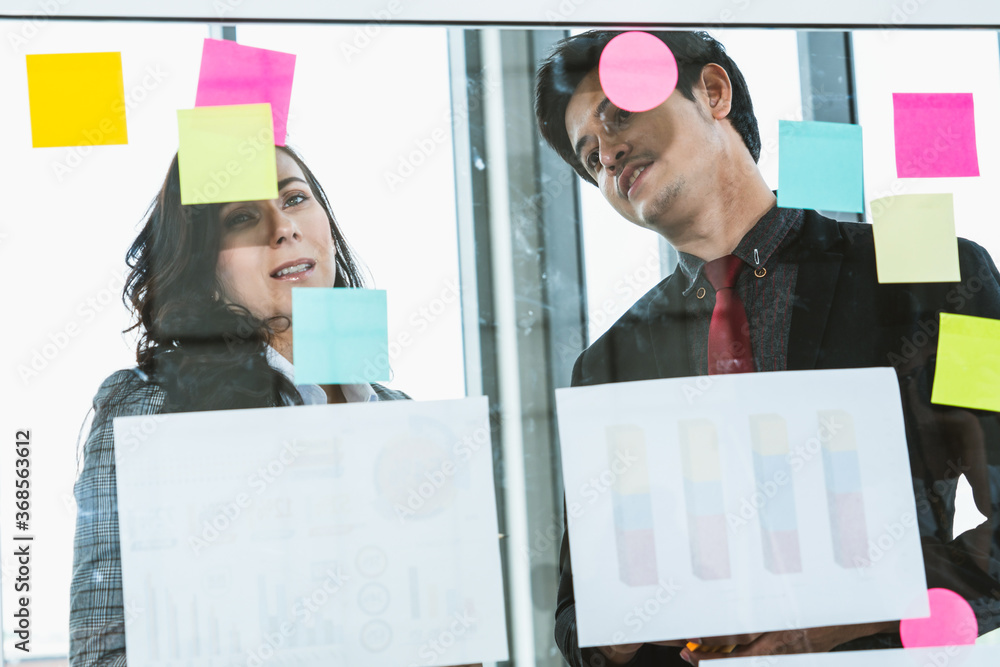 Business people work on project planning board in office and having conversation with coworker frien