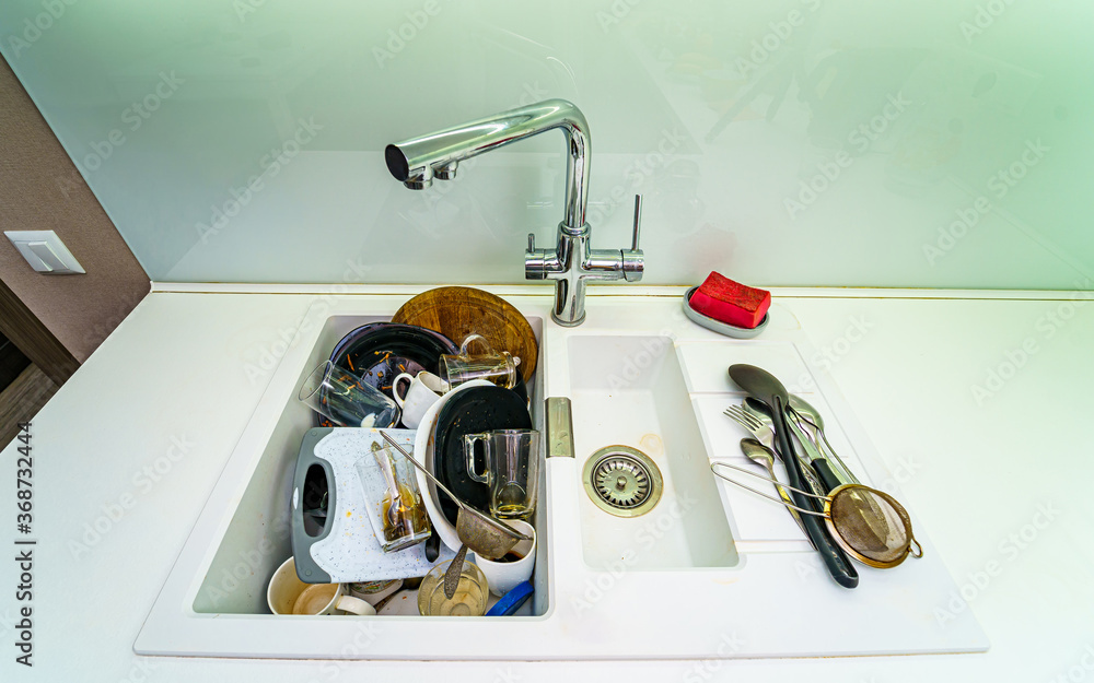 Pile of dirty dishes in white sink. View from above.