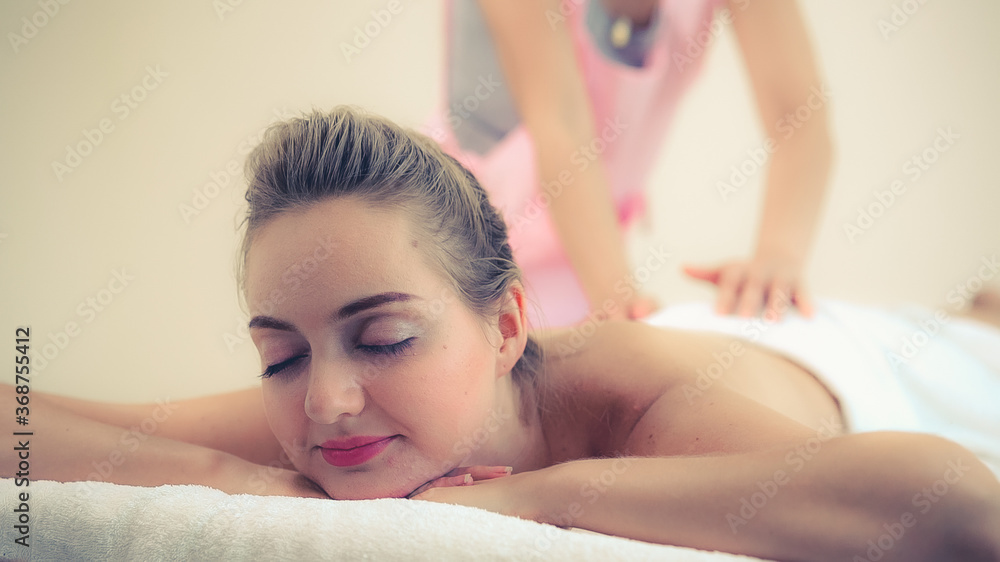 Relaxed woman getting back massage in luxury spa with professional massage therapist. Wellness, heal