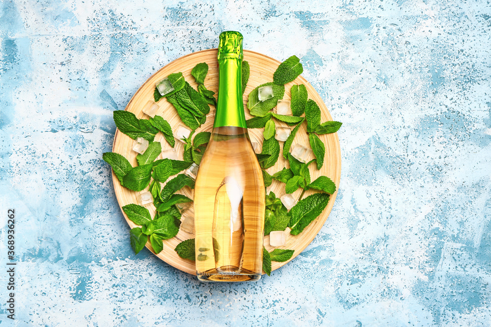 Bottle of champagne, mint and ice cubes on color background