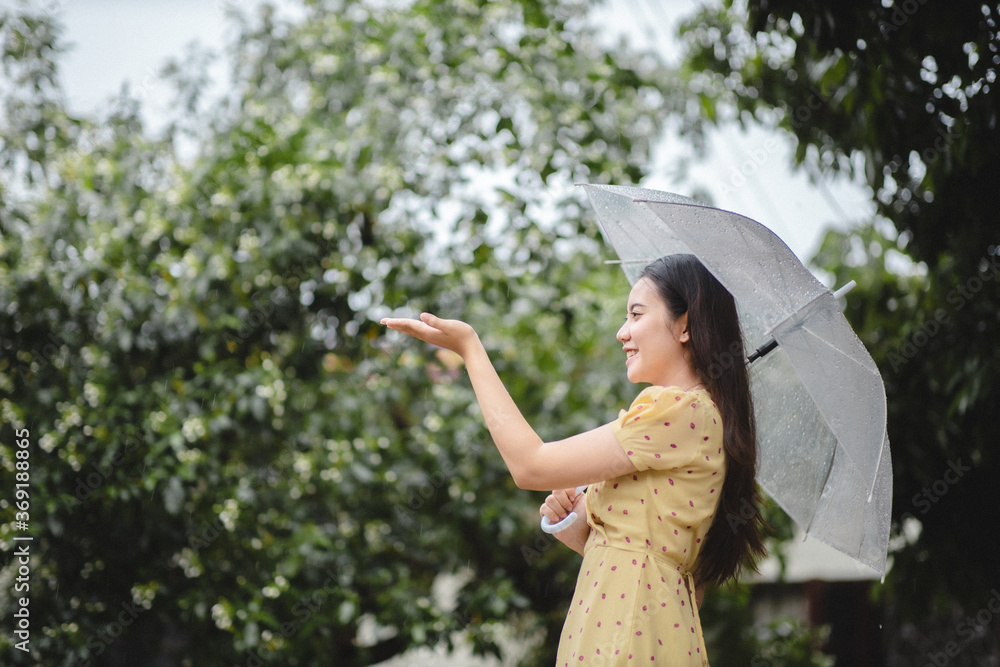 雨天，亚洲女人微笑着用手触摸户外的雨水。