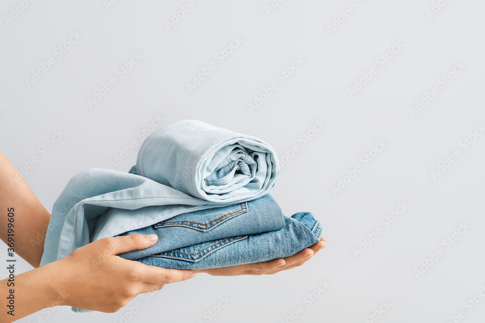 Female hands with stylish jeans pants on grey background