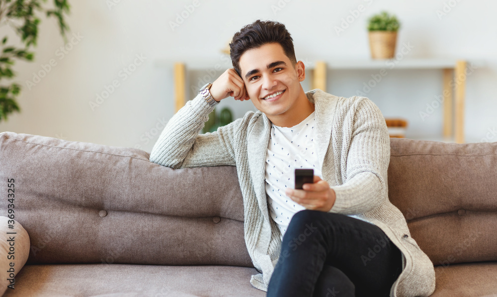 Cheerful young man watching TV.