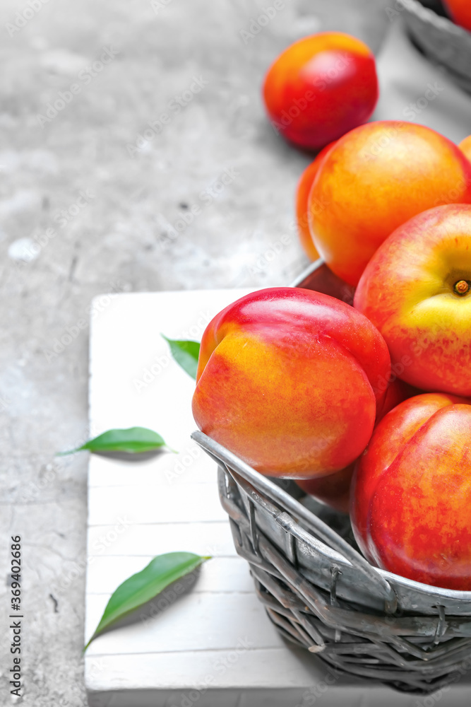 Sweet ripe nectarines in basket on grey background