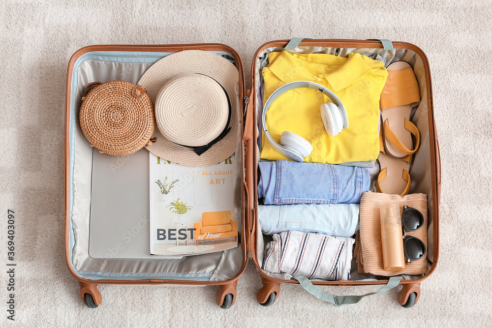 Packed suitcase with belongings on floor. Travel concept