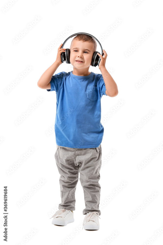 Cute little boy listening to music on white background