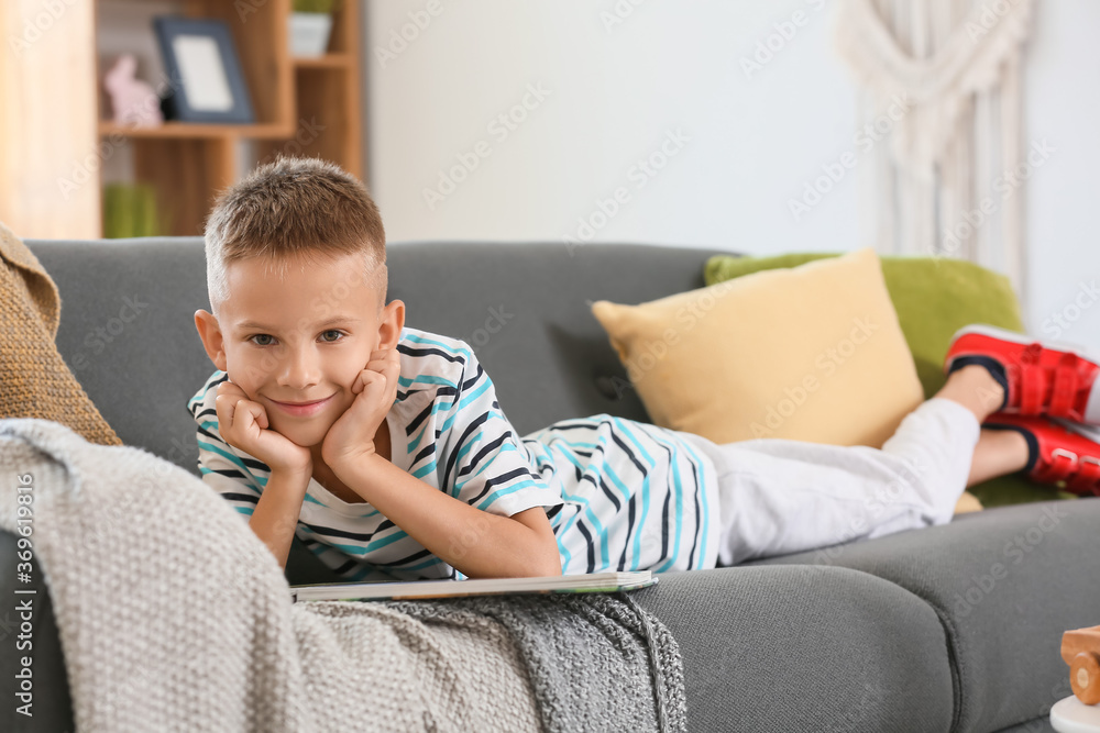 Cute little boy reading book at home