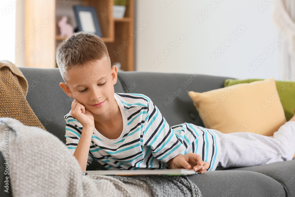 Cute little boy reading book at home