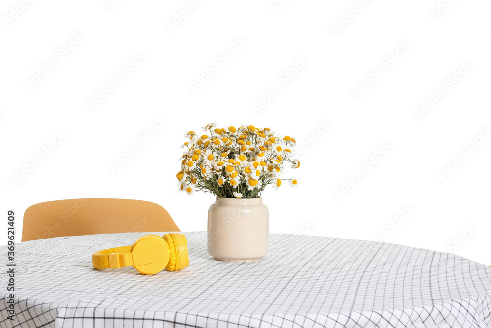 Vase with flowers and headphones on table against on white background