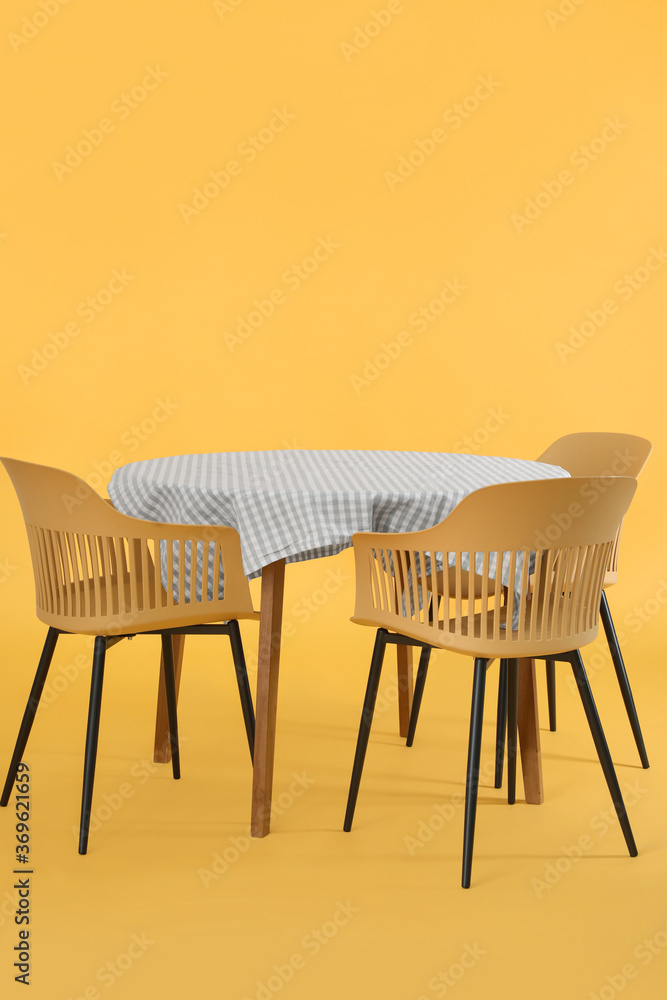 Dining table with chairs on color background