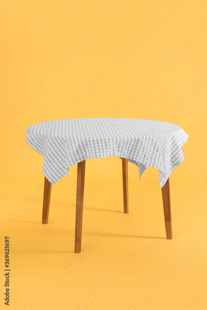 Dining table with tablecloth on color background