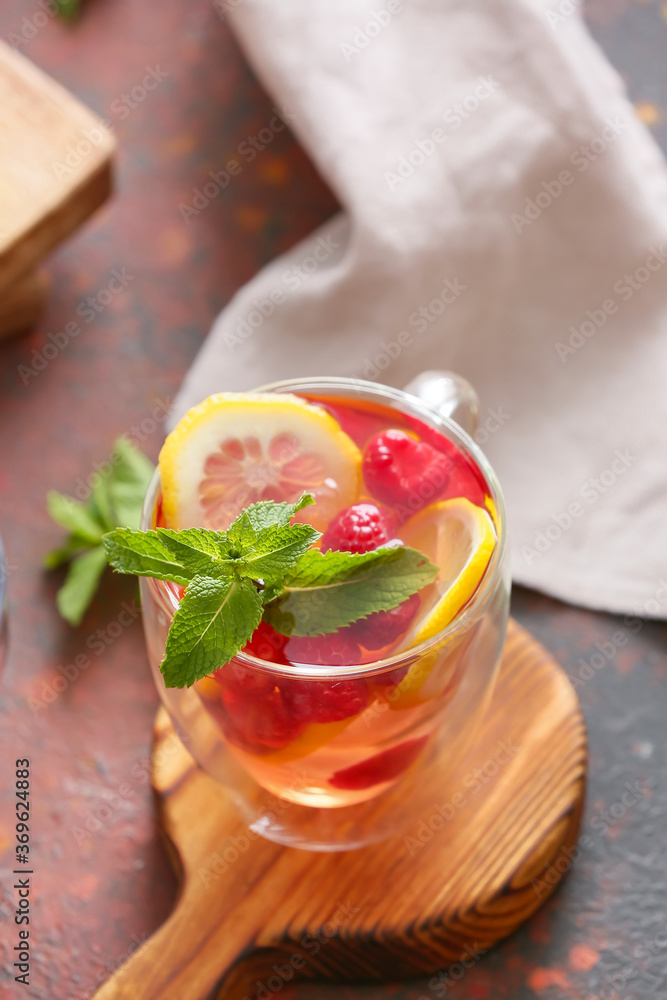 Cup of cold raspberry tea on color background