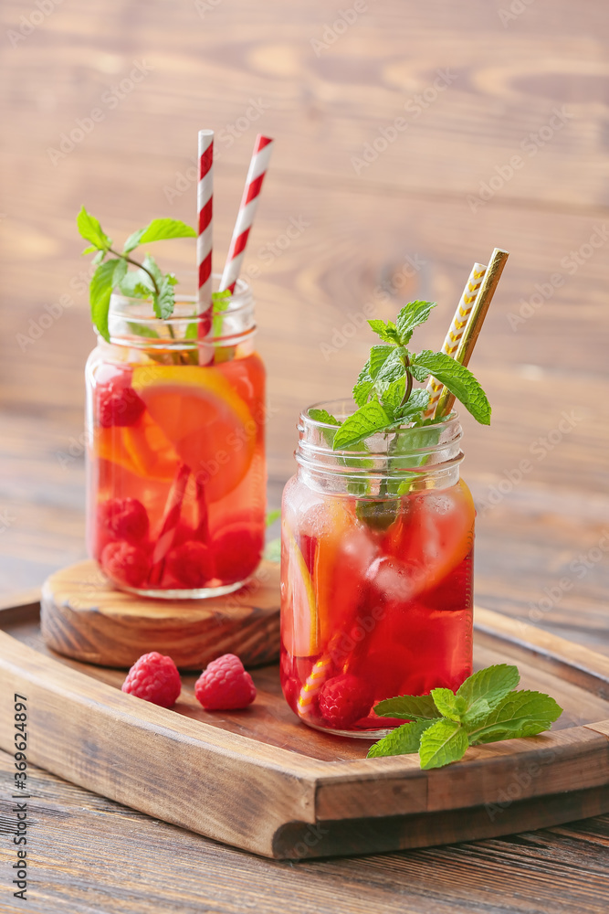 Mason jars of cold raspberry tea on table