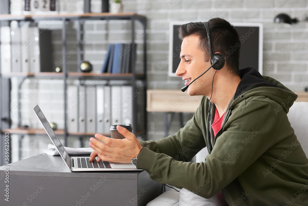 Man with headphones and laptop working in office