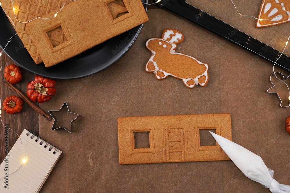 Young woman is decorating Christmas Gingerbread House cookies biscuit at home with frosting topping 