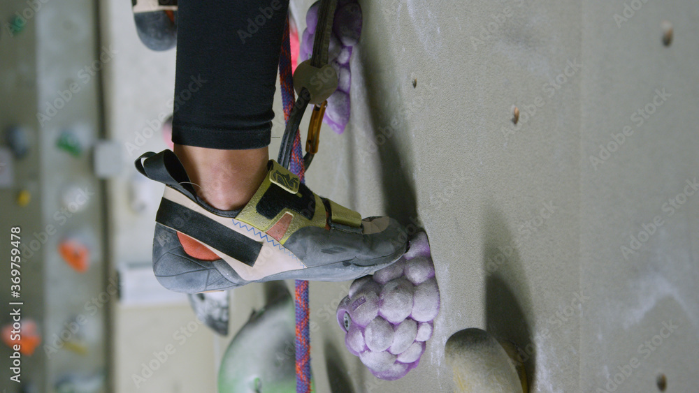 CLOSE UP: Teenager pushes off her foot resting on a foothold resembling grapes