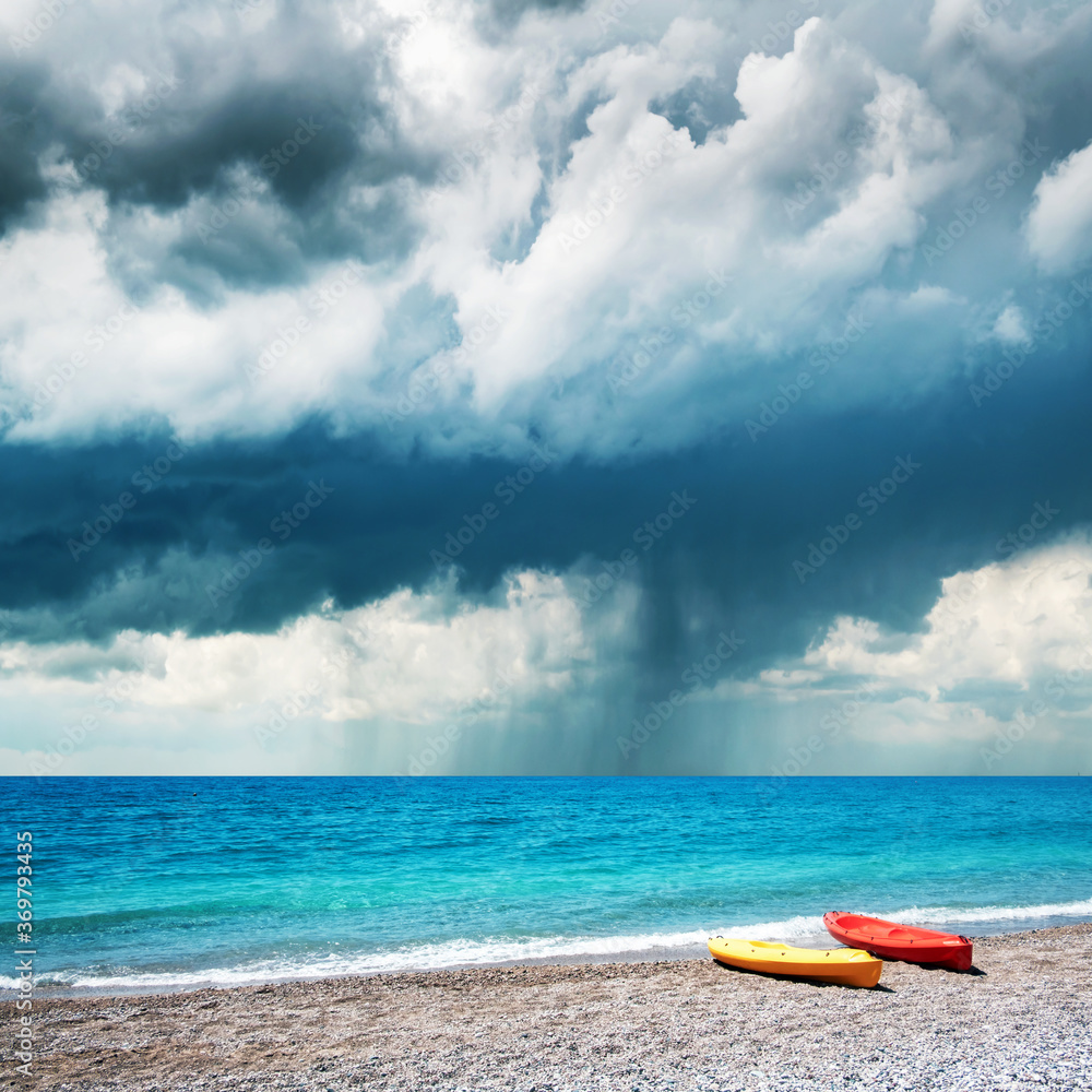 海边的两艘皮划艇。背景是戏剧性的暴雨云。夏令时间