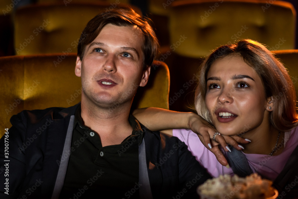 Man whispering to his girlfriend and tell something about story in movie at cinema