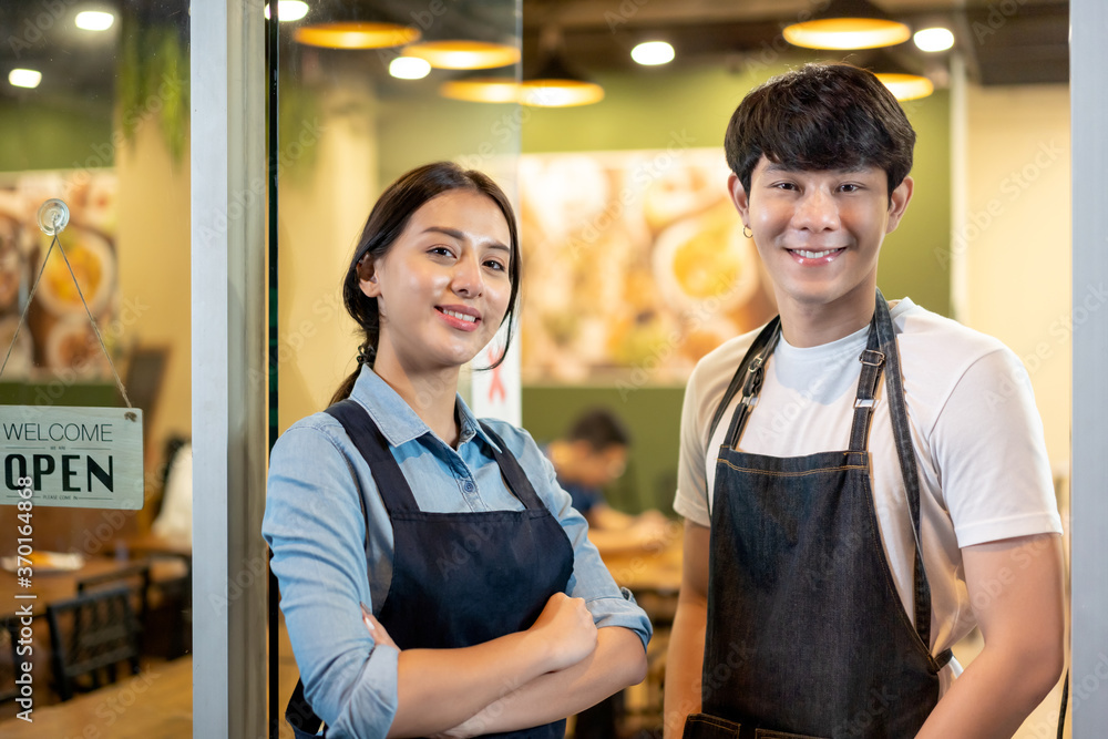 Portrait of Young couple restaurant owner in front of restaurant . waitresses in aprons smiling stan