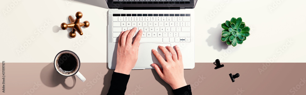 Woman using a laptop computer with office supplies