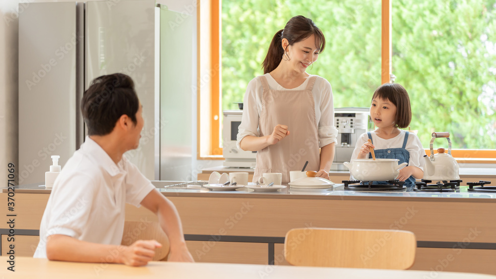 キッチンで料理を作る女の子と両親