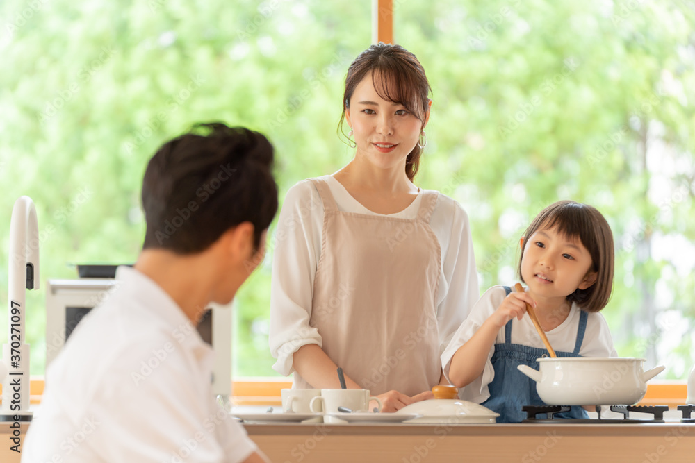 キッチンで料理を作る女の子と両親