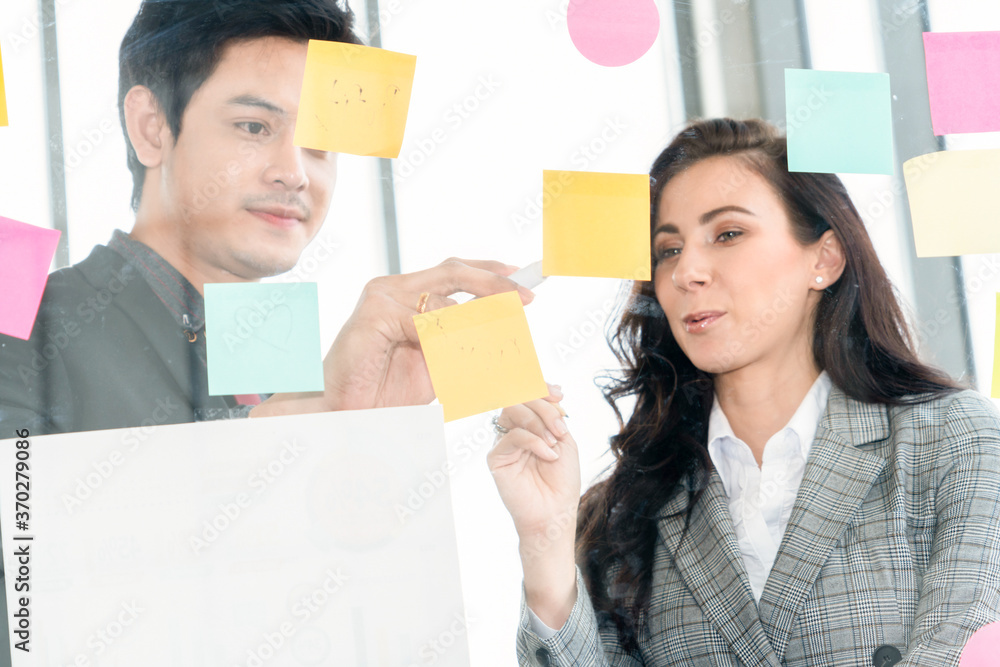 Business people work on project planning board in office and having conversation with coworker frien