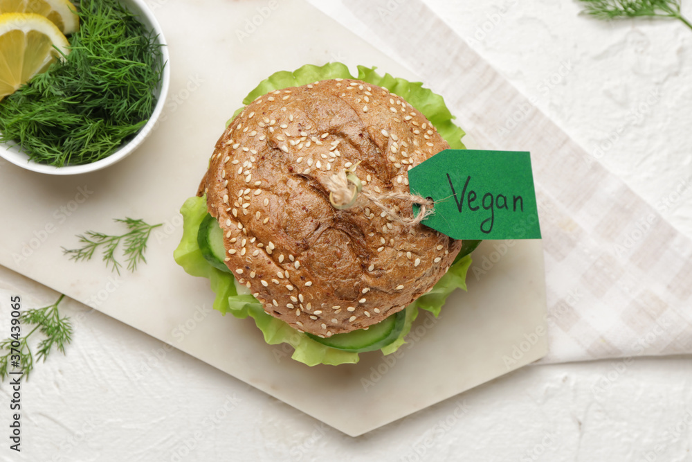 Board with tasty vegan burger on white background