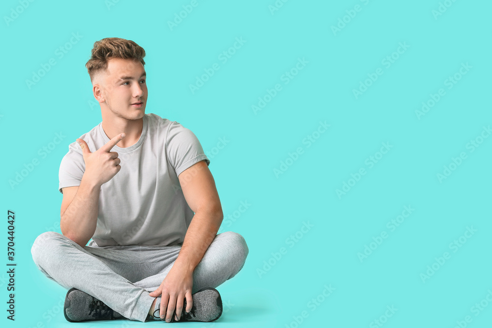 Young man showing something on color background