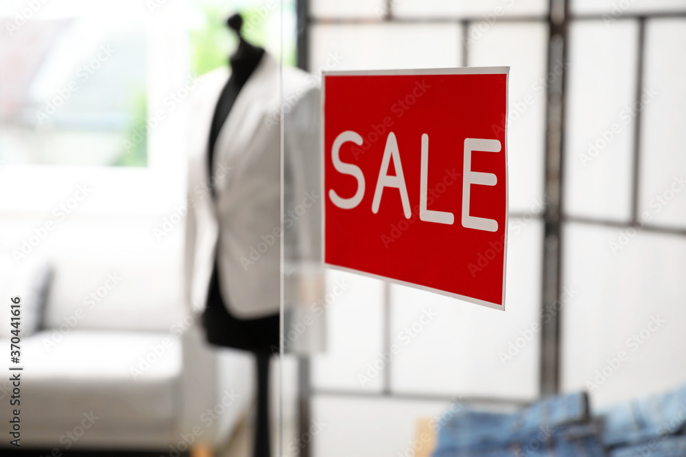 Sticker with word SALE on transparent door of modern clothes store