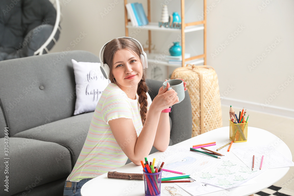 Young woman coloring picture at home